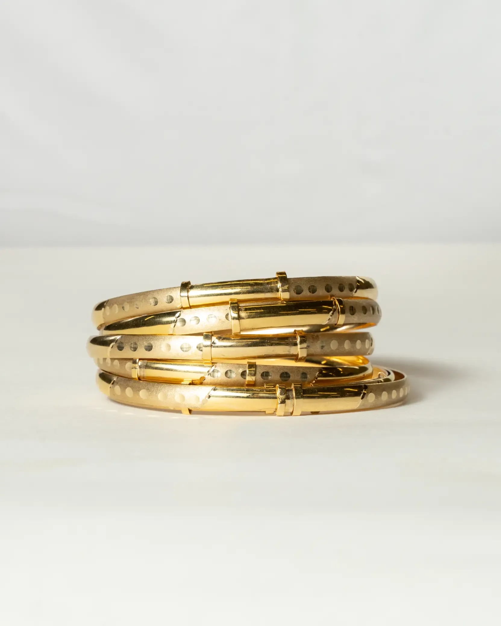 Stack of shiny gold bracelets arranged neatly on a surface.